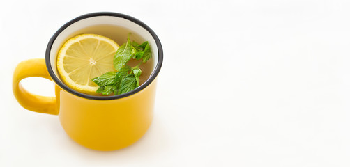 Side view of a cup of tea with lemon and mint on a light background. Space for text.