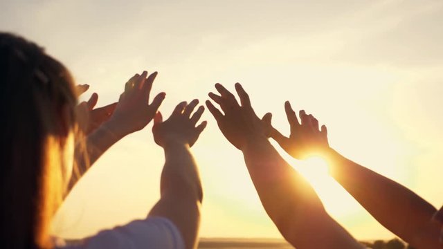 People's hands reach for the sun at sunset. Happy family together. Teamwork. A cry for help, People together in prayer turn to the sun.