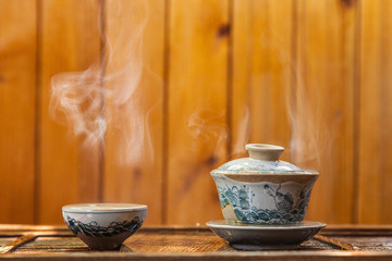 Cup of chinese tea with cloud of steam on wooden background