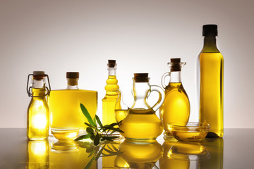Assorted glass containers with olive oil backlit on glass table