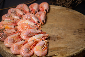 Boiled shrimp. Shrimps lie on a wooden board. Decorated around with dry greenery. Seafood