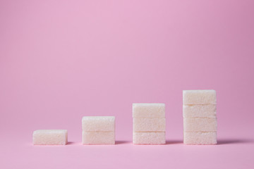 Sugar cubes on a pink background. Cubes are stacked in several columns in ascending order