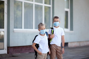 Back to school. Schoolchildren in masks with backpacks on the doorstep of the school