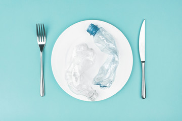 Plate with plastic bottles on blue background.