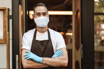 Young man cafe owner with face mask opens