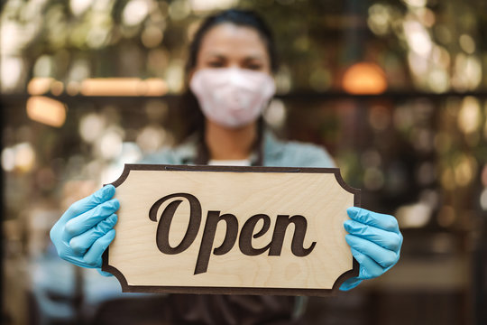 Woman coffee shop owner with face mask opens
