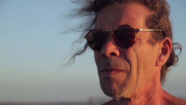 portrait d'un homme mature revenant de la p&ecirc;che au couch&eacute; de soleil. on aper&ccedil;oit un peu de vent dans ses cheveux.