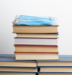 stack of various books and disposable medical masks on a white background, concept of visiting libraries