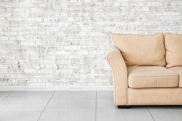 Modern sofa near brick wall in room