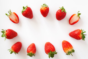 Fototapeta na wymiar Oval frame of whole and halved strawberries on white background. Isolated. Copy space.