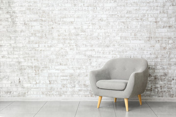 Modern armchair near brick wall in room