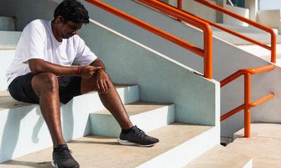 Naklejka premium Close up Asian young athlete sport runner black man wear modern time smart watch he sitting resting before training running at the outdoor street health park, healthy exercise before workout concept