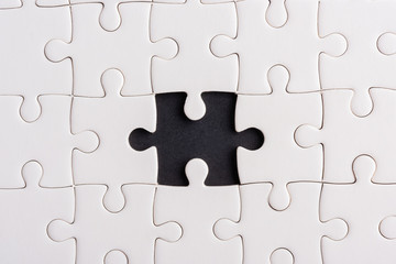 Top view flat lay of paper plain white jigsaw puzzle game texture incomplete or missing piece, studio shot on a black background, quiz calculation concept