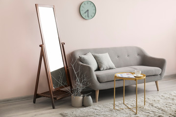 Big mirror with sofa near color wall in room