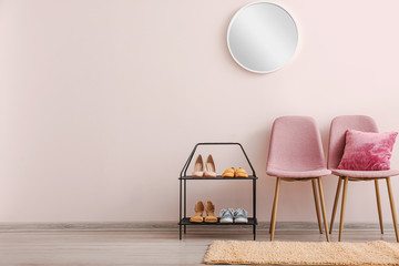 Stylish interior of hallway with shoe stand, chairs and mirror