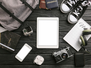Composition with tablet computer and travel accessories on wooden background