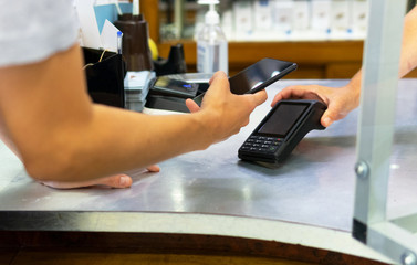 Young woman paying with mobile in a store.