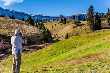 Fototapeta premium Gray-haired tourist photographs a landscape