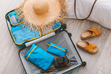 Suitcase and set of travel organizers with belongings at home