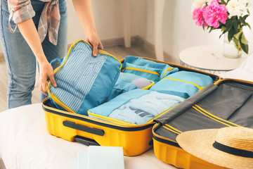 Woman packing clothes before journey at home