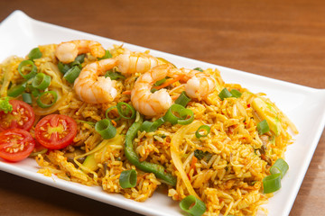 Chinese fried rice with prawns, on wooden background. Typical Asian food.