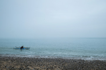 Fototapeta premium Two people Kayaking on the sea on a dark grey day