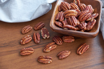 pecan nuts in wood bowl on old brown table, selective focus. top view. Healthy food and snack.