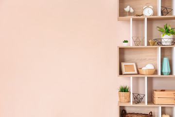 Wooden rack with decor near color wall in room