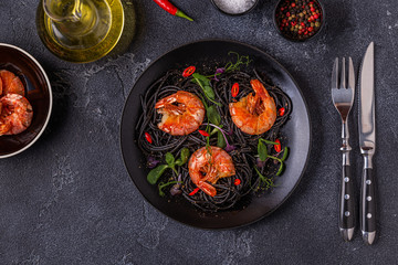 Italian pasta black spaghetti with shrimp and microgreens.