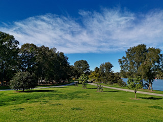 Fototapeta na wymiar Beautiful view of a park with green grass, tall trees and paved trail for walking and cycling, Reid Park, Parramatta Cycleway, Rydalmere, Sydney, New South Wales, Australia 