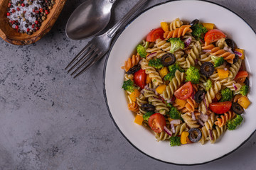 Pasta salad with tomato, broccoli, black olives.