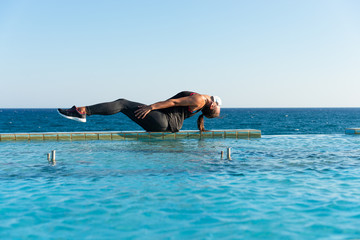 Young woman with protective surgical face mask performing yoga stretching exercises outdoor during covid-19 coronavirus pandemic