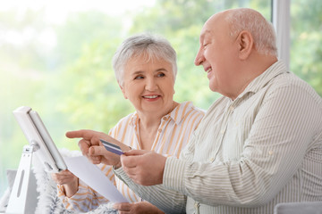 Senior couple with tablet computer and credit card at home