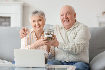 Senior couple with savings in jar at home