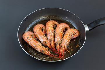 Roasted big shrimps (Langoustine) with rosemary and lemon in frying pan. Seafood