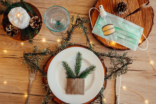 Christmas Eve Holiday Party Decorated Table Set With Disposable Medical Mask And Alcohol Hand Sanitizer Bottle. Coronavirus (Covid 19) Spreading Prevention Concept. Christmas Micro Led Lights Wire.