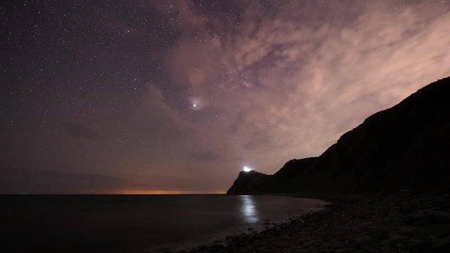 Amazing time lapse with Milky Way galaxy, moving clouds, plane trails and meteor shower, during Perseid stream over rocky Black sea coast and cape Emine with the lighthouse, Bulgaria