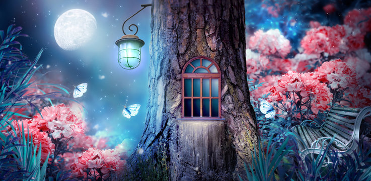 Magical fantasy elf or gnome house in tree with window and lantern, bench in enchanted fairy tale forest with fabulous fairytale blooming pink rose flower garden and shiny glowing moon rays in night