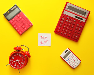 Alarm clock with calculators on color background. Concept of tax deadline
