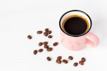 Pink сup of fresh coffee with grains on white wooden background. Copy space