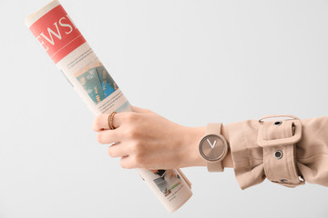 Woman with stylish wrist watch and newspaper on white background
