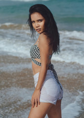Balinese girl with brackets on her teeth on the beach on a bright sunny day