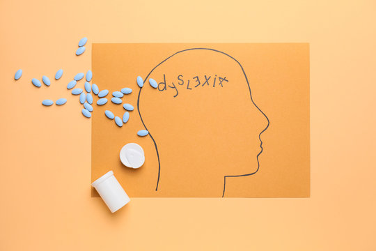 Imaging of human head with pills and and word DYSLEXIA on color background