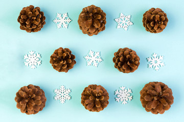 Top view of holiday composition made of pine cones and white snowflakes on colorful background. Winter time and Christmas concept with copy space