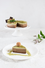 A slice of chocolate cake with mint jelly and matcha on a white plate. Sugar, lactose, gluten free. Healthy food, diet, vegetarian.