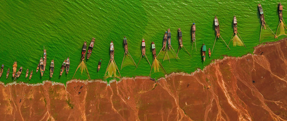 Aerial view of Ben Nom fishing village, a brilliant, fresh, green image of the green algae season on Tri An lake, with many traditional fishing boats anchored © CravenA