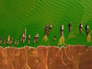 Aerial view of Ben Nom fishing village, a brilliant, fresh, green image of the green algae season on Tri An lake, with many traditional fishing boats anchored