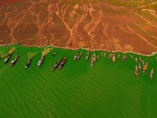 Aerial view of Ben Nom fishing village, a brilliant, fresh, green image of the green algae season on Tri An lake, with many traditional fishing boats anchored