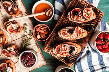set of bruschettas with figs and goat cheese, berries, nuts, honey. crostini with toasted baguette, blue cheese, onion jam