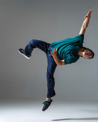 Cool young guy breakdancer jumps dancing hip-hop isolated on gray background. Dance school poster....